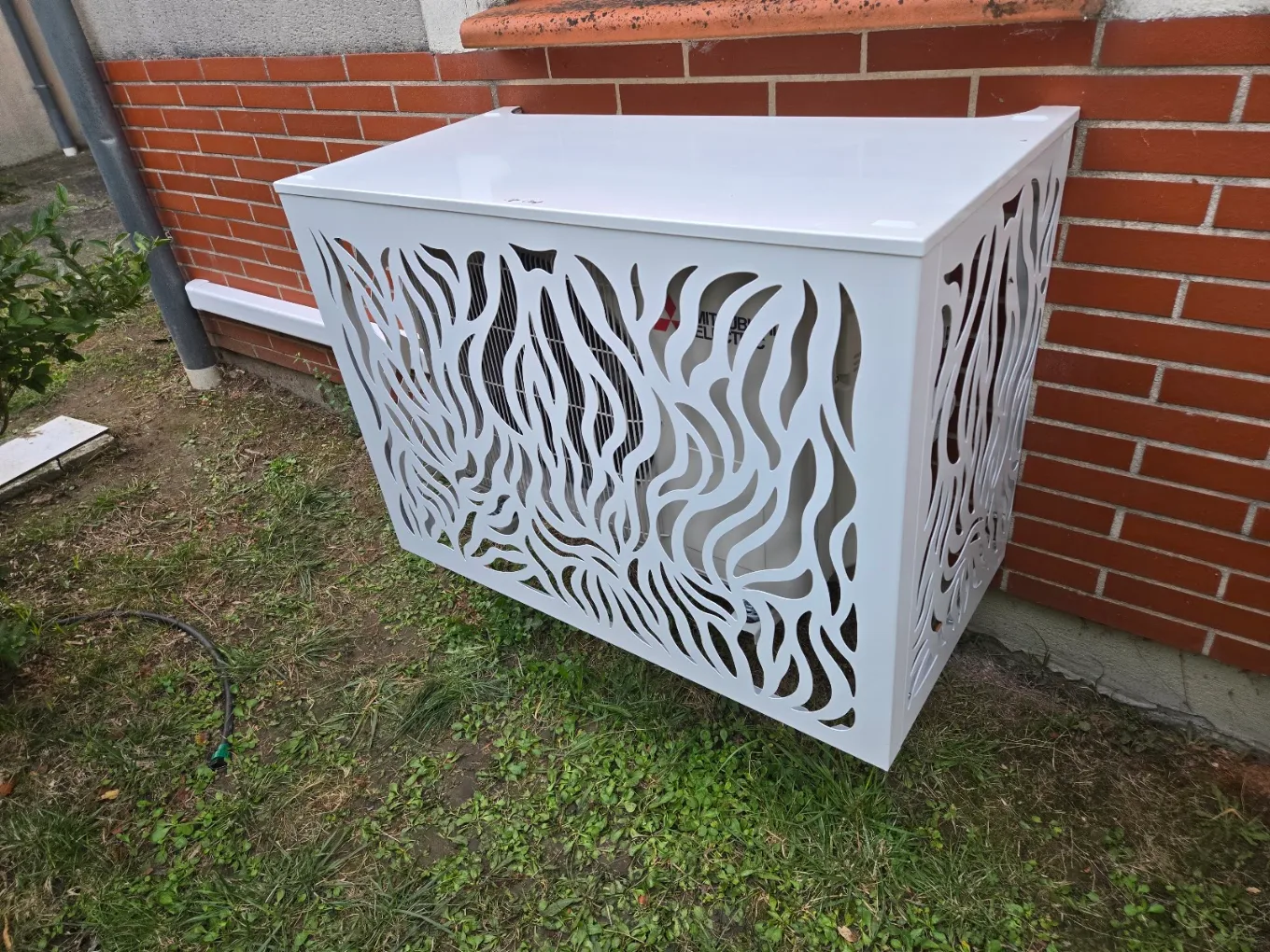 Cache décoratif blanc ajouré autour d’une unité extérieure de climatisation